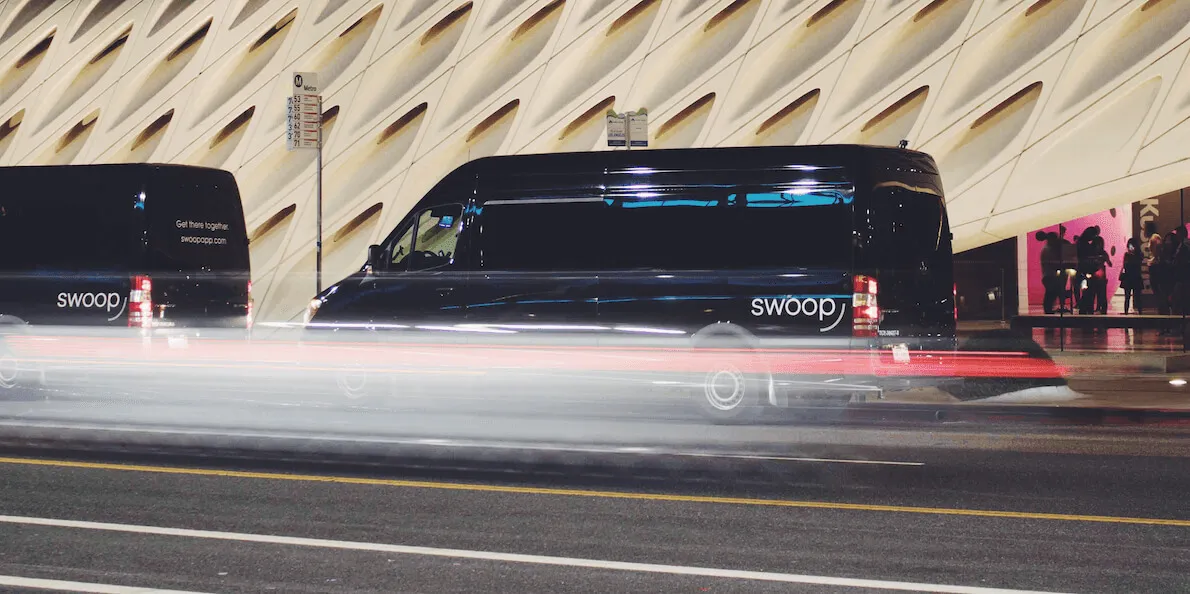 Black Swoop vans driving past a modern building