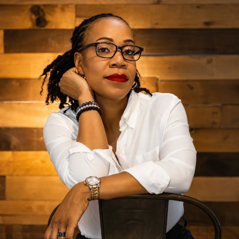 Portrait of a woman in glasses leaning on a chair