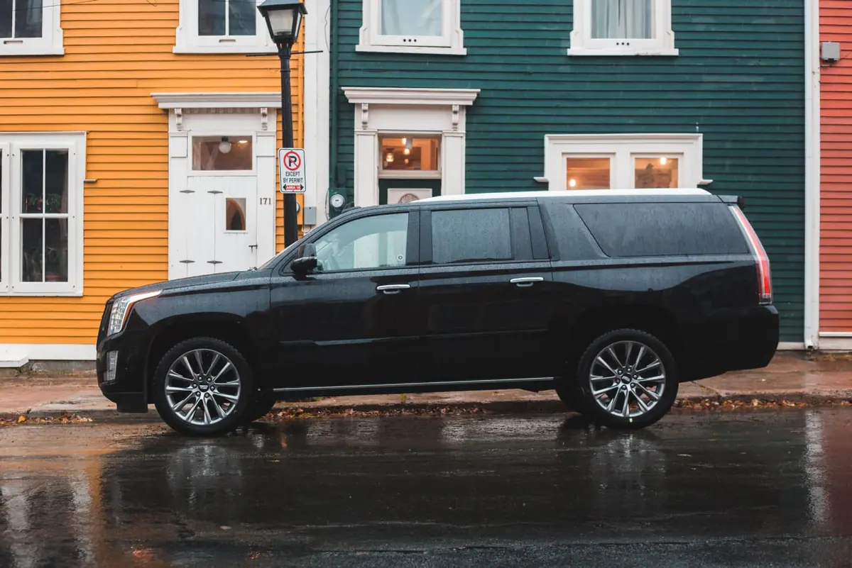 Black Cadillac Escalade parked on street in front of blue house in Atlanta by Erik Mclean on Unsplash