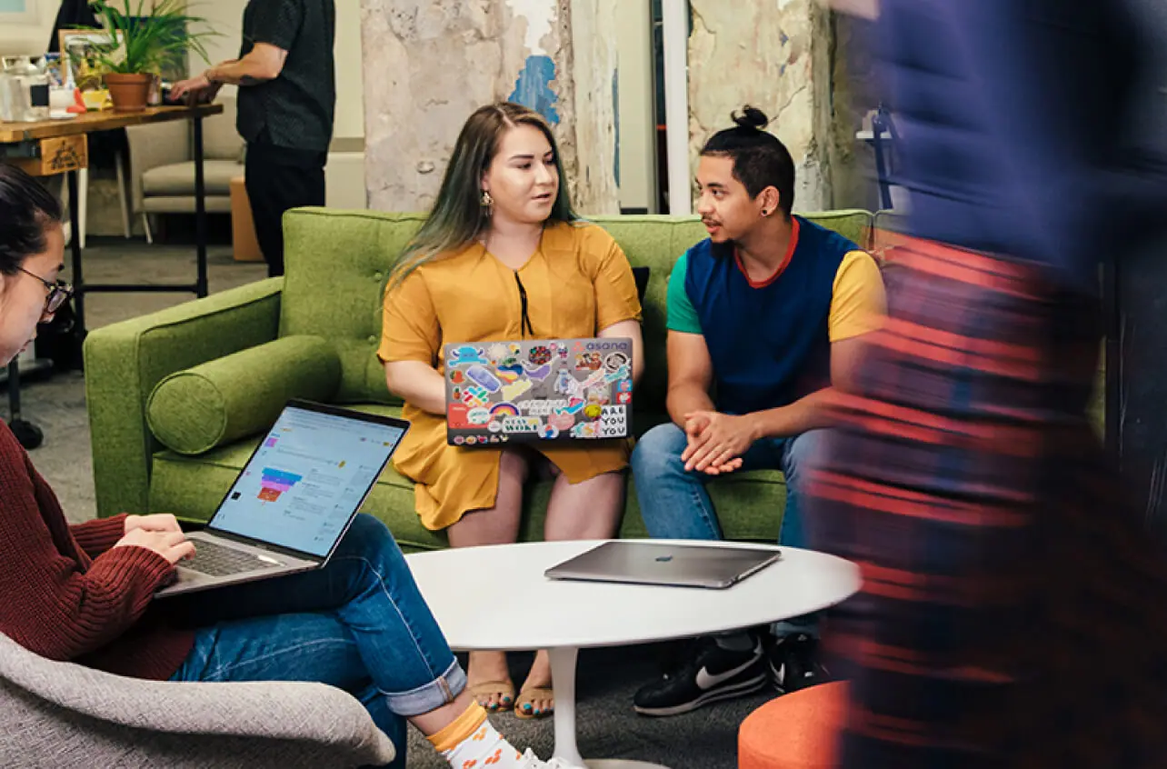 Team members working on laptops in a lounge