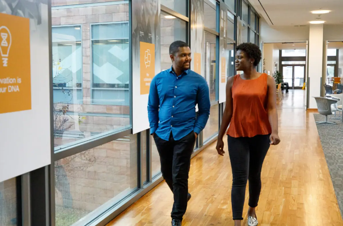 Two colleagues walking through an office hallway