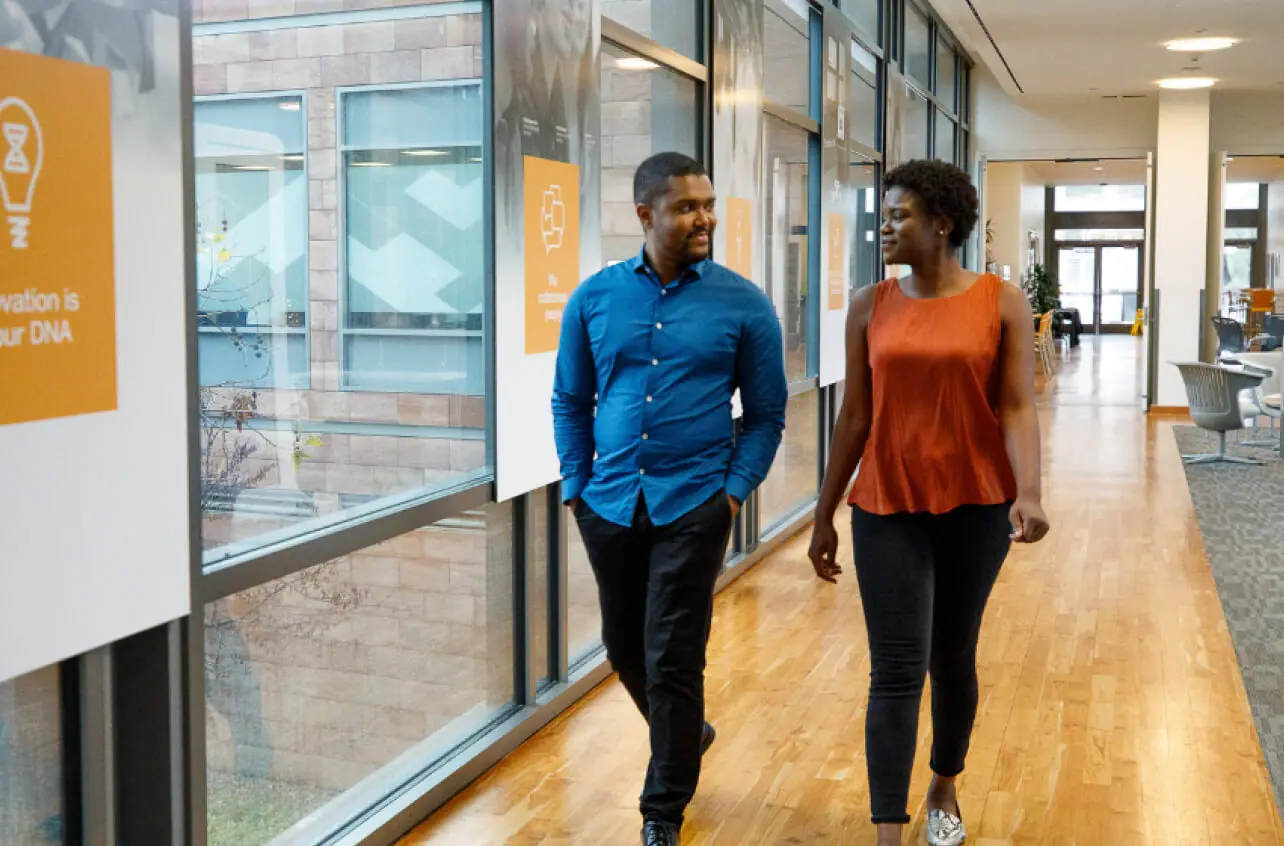 Two colleagues walking through an office hallway