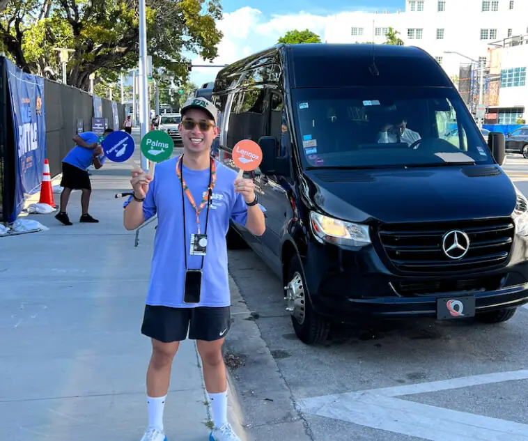 Swoop coordinator holding a sign next to a black Sprinter van