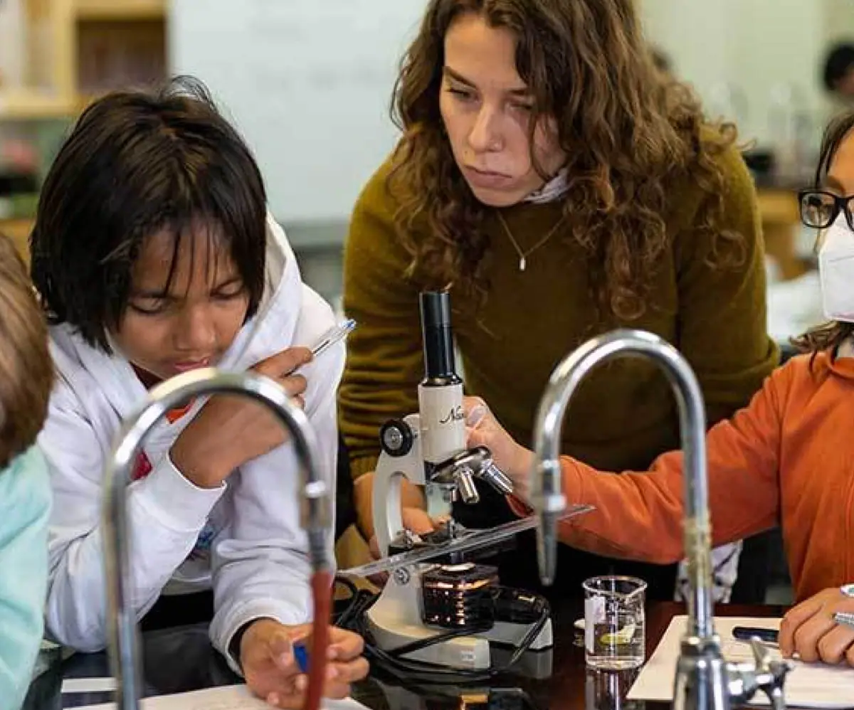 Teacher helping students with a microscope in a science lab