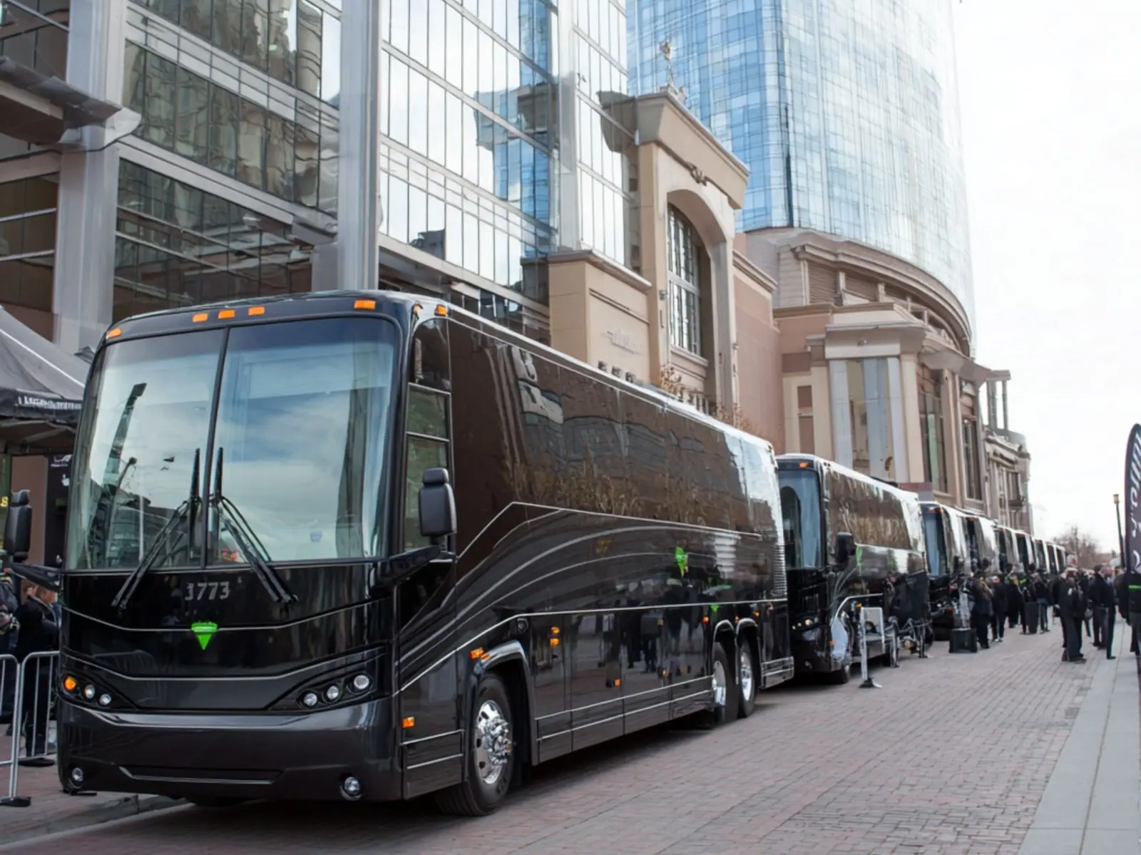 Black coach buses lined up outside a convention center