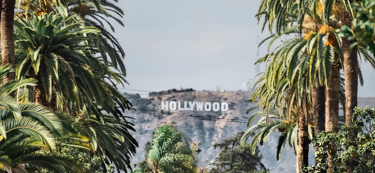 Hollywood sign on the hills of Los Angeles behind palm trees