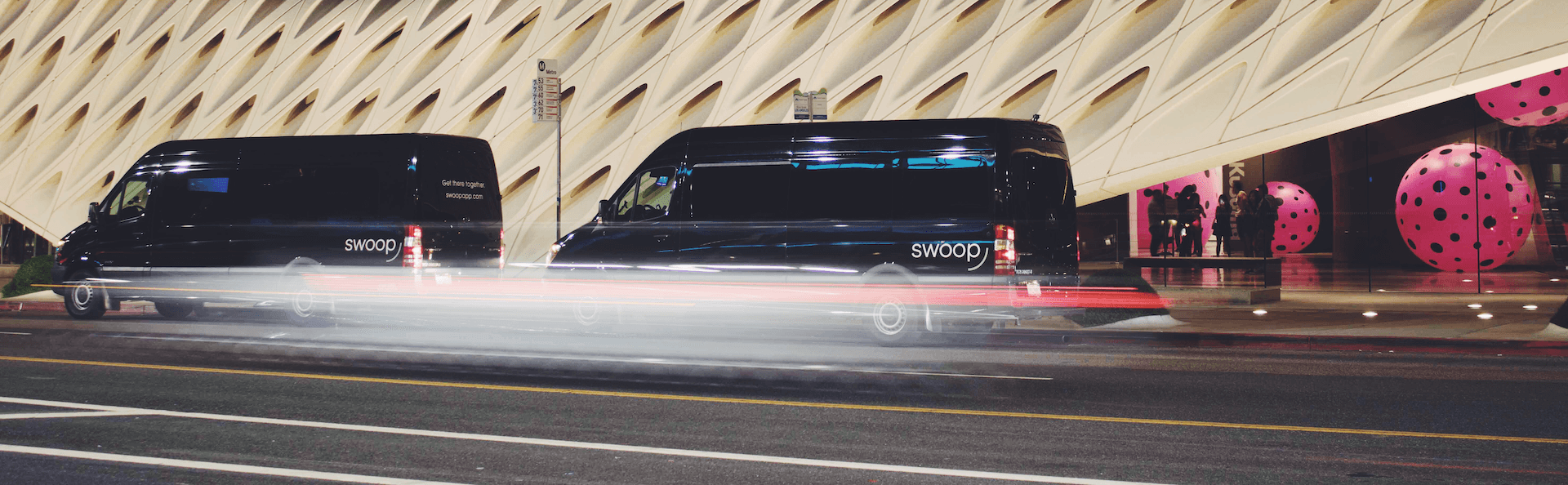 Black Swoop vans driving past a modern building